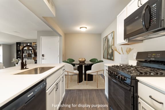 newly renovated kitchen featuring black appliances, white cabinets, quartz countertops, and luxury vinyl planking at Bristol Square & Golden Gate Apartments in Wixom, MI