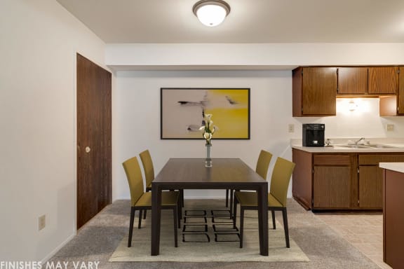 a dining room with a table and chairs and a kitchen in the background at Beacon Hill and Great Oaks Apartments, Rockford, IL