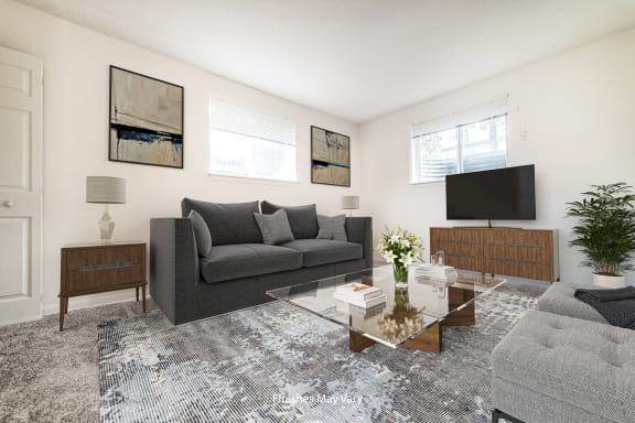 a living room with a gray couch and a glass coffee table