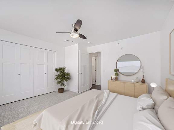 A bedroom with a bed, dresser, mirror, and a ceiling fan at Dodson Pointe Apartment Homes, Rogers
