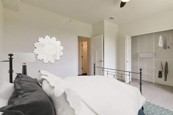 A spacious bedroom with a bed and a closet with organizers at Dodson Pointe Apartment Homes, Rogers, AR