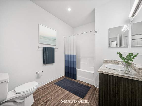 A bathroom with a toilet, sink, and mirror A bathroom with a toilet, sink, and mirror at Dodson Pointe Apartment Homes, Rogers