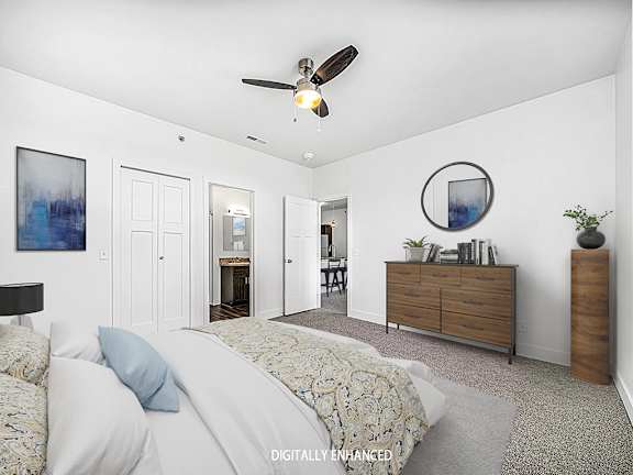 A bedroom with a bed, dresser, ceiling fan and an ensuite A bedroom with a bed, dresser, ceiling fan and an ensuite at Dodson Pointe Apartment Homes, Rogers