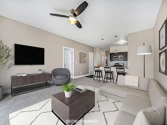 A living room with a grey armchair, a white sofa, a wooden coffee table A living room with a grey armchair, a white sofa, a wooden coffee table at Dodson Pointe Apartment Homes, Rogers