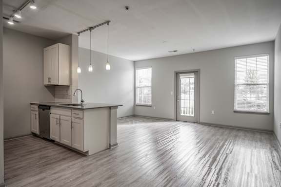 the living room and kitchen in a new home with white walls and wood floors at Bella Vista Apartments, Fishers, IN