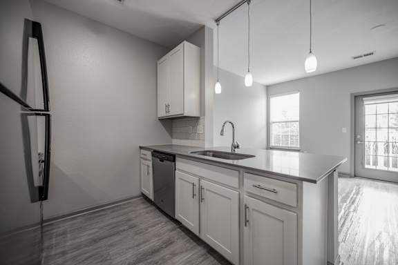 an empty kitchen with white cabinets and a black counter top at Bella Vista Apartments, Fishers, IN, 46038