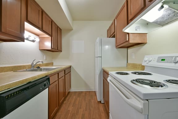 a kitchen with white appliances and wooden cabinets at Perry Place Apartments, Grand Blanc