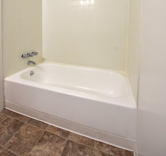 a white bath tub in a white tiled bathroom