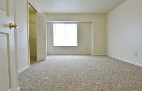 Empty carpeted bedroom with large window and alcove at Heatherwood Apartments, Michigan, 48439