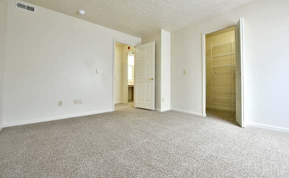 Empty carpeted bedroom with walkin closet and bathroom access at Heatherwood Apartments, Grand Blanc, MI 48439