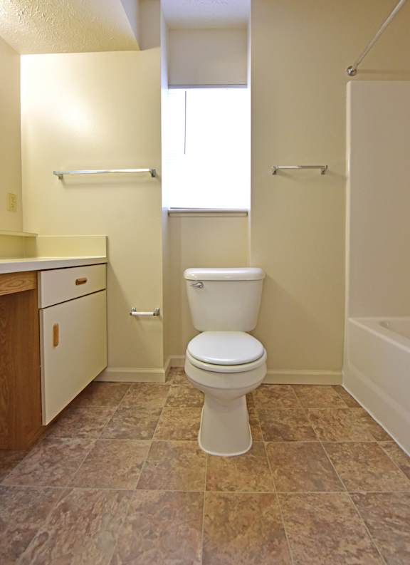 Bathroom with toilet and shower alcove storage at Heatherwood Apartments, Grand Blanc, MI