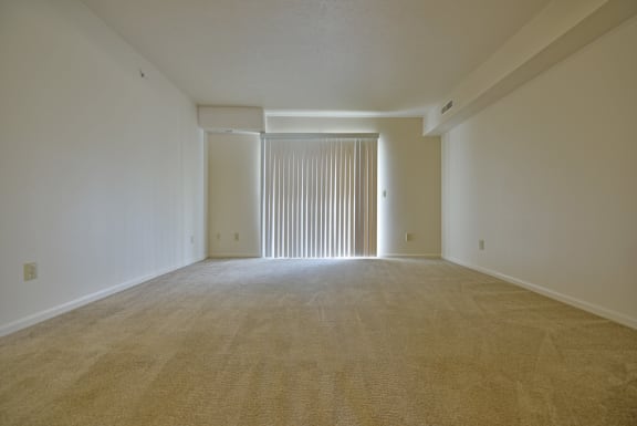an empty living room with white walls and a sliding glass door at Heatherwood Apartments, Michigan