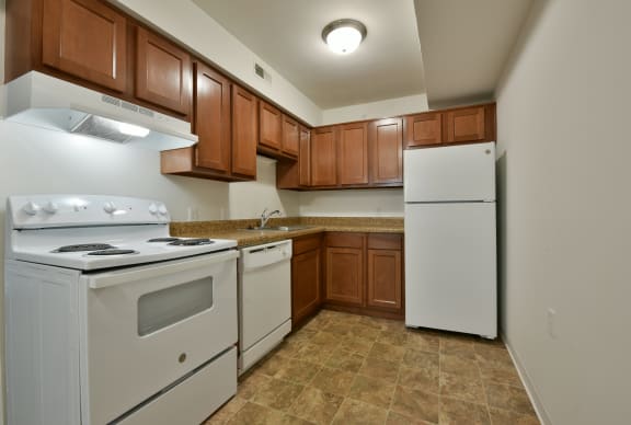 a kitchen with white appliances and wooden cabinets and a white refrigerator  at Charter Oaks Apartments, Michigan