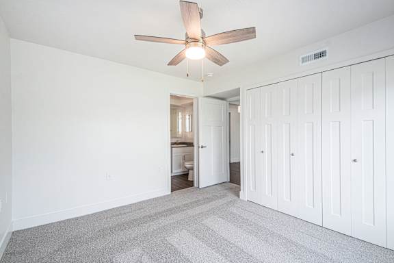 an empty living room with a ceiling fan and white closets