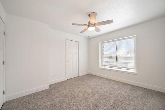 Bedroom with a ceiling fan and large window at Dupont Lakes Apartments in Fort Wayne, IN
