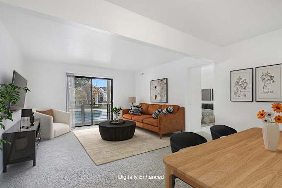 A living room with a brown sofa and a wooden table at Dupont Lakes Apartments in Fort Wayne, IN