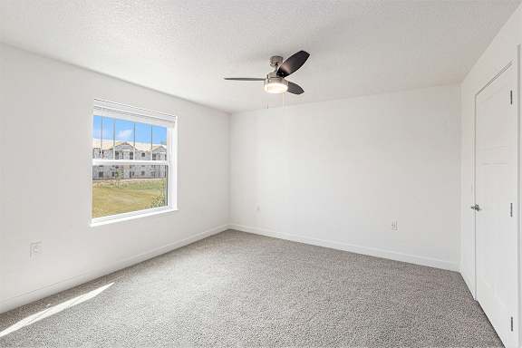 A bedroom with a ceiling fan and a window showing a view at Eagle Ridge Apartment Homes, Traverse City, MI 49685