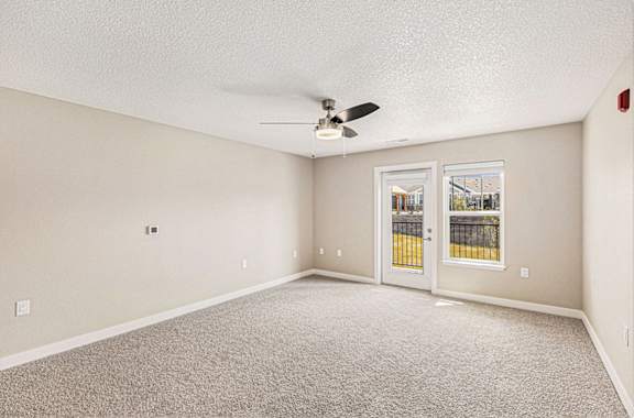 A living room with a ceiling fan and a french door to the outside at Eagle Ridge Apartment Homes, Traverse City, MI 49685