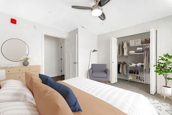 A bedroom with a bed, chair, and a walk in closet with organizers at Eagle Ridge Apartment Homes in Traverse City, MI
