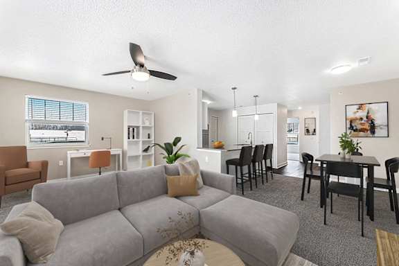 An enlarged living room with a grey couch and a ceiling fan at Eagle Ridge Apartment Homes in Traverse City, MI