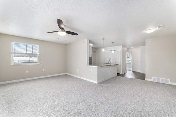 A spacious living room with a ceiling fan and a window at Eagle Ridge Apartment Homes, Traverse City