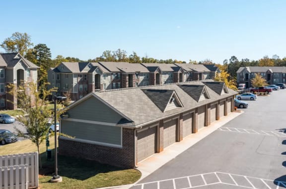 a row of houses in a parking lot with trees in the background at Emerald Creek Apartments, Greenville, SC