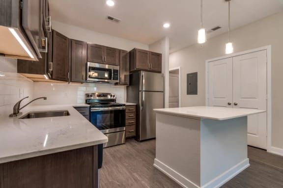 a kitchen with dark wood cabinets and white countertops at Emerald Creek Apartments, Greenville