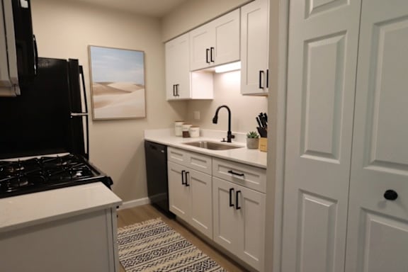 A kitchen with white cabinets and a black stove top oven.