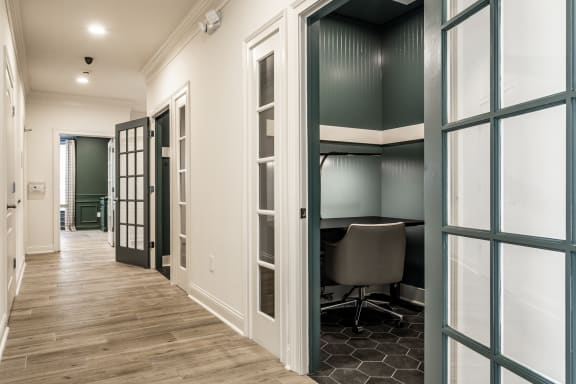 a hallway with a desk and a chair in a room with glass doors  at Alexandria of Carmel Apartments, Carmel, Indiana