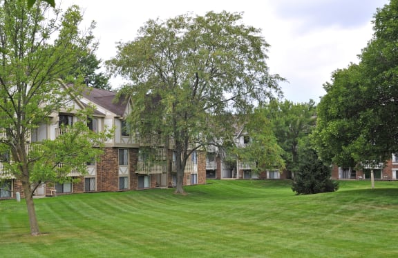 a large grassy area with trees in front of an apartment complex  at Fox Pointe Apartments, East Moline, Illinois