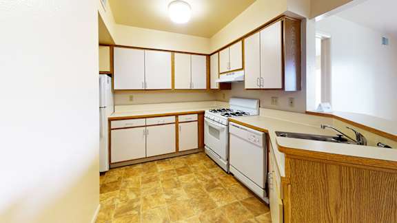 A kitchen with white appliances and wooden cabinets at Emerald Park Apartments, Kalamazoo, Michigan