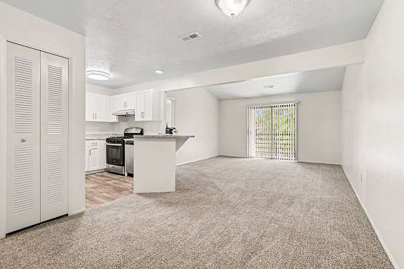 A kitchen with white cabinets and a sliding glass door to a balcony at Emerald Park Apartments, Kalamazoo, Michigan