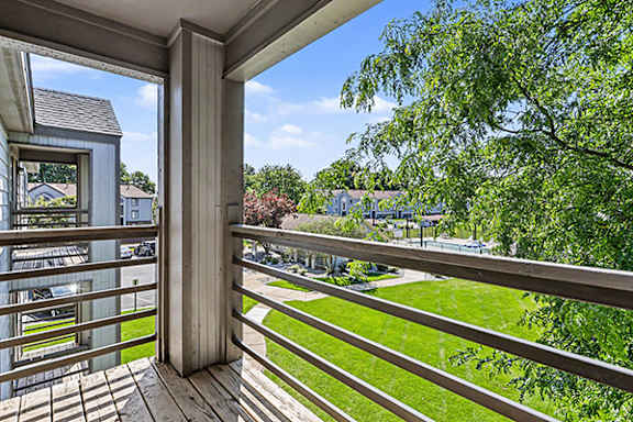 A balcony with a view of a green lawn at Emerald Park Apartments in Kalamazoo, MI