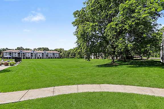 A grassy area with a building in the background at Emerald Park Apartments in Kalamazoo, MI