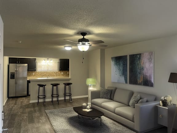 A living room with a grey couch and a ceiling fan.