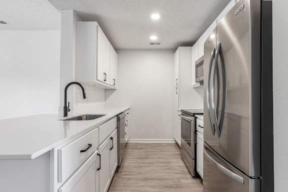 an empty kitchen with white cabinets and stainless steel appliances at Latitudes Apartments, Indianapolis, IN