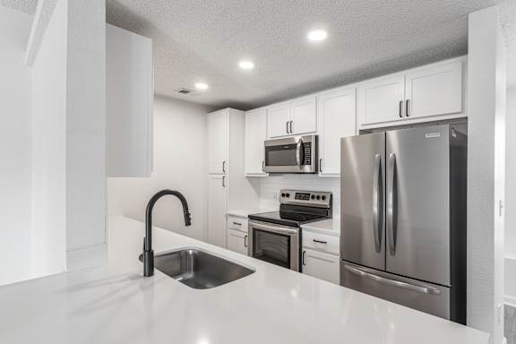 a kitchen with white cabinets and stainless steel appliances at Latitudes Apartments, Indianapolis, IN