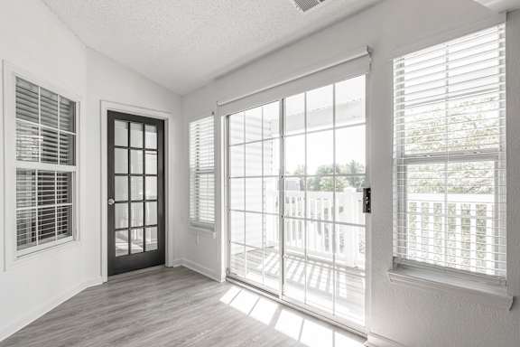 an empty living room with large windows and a door to a balcony at Latitudes Apartments, Indianapolis, Indiana