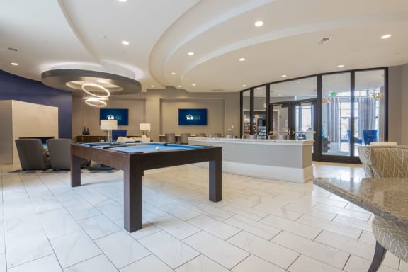 Resident lounge with a pool table and a bar and TVs at Avant Apartments in Carmel, IN
