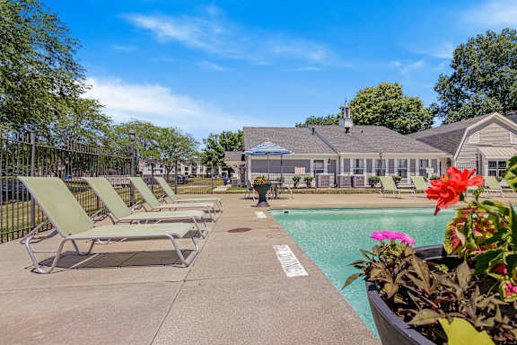 A pool area with sun loungers and a building in the background at Bay Pointe Apartments, Lafayette, IN