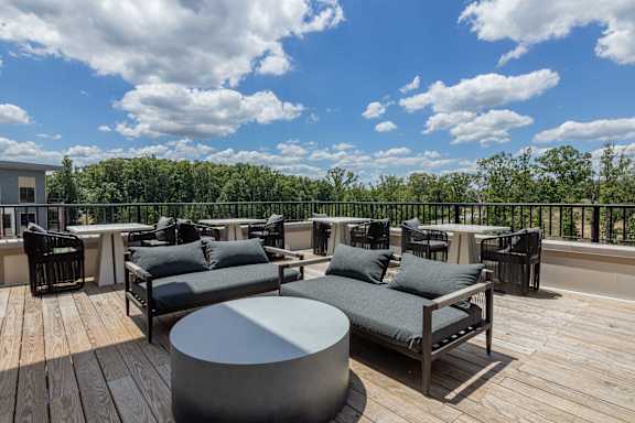 A wooden deck with grey couches and tables at Luxe 360 on Centerpointe Apartments, Virginia, 23114