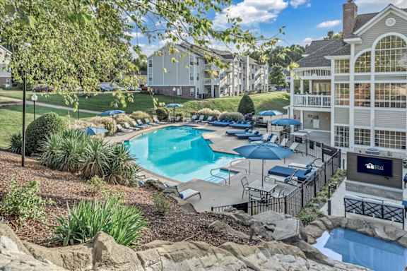 a resort style swimming pool with umbrellas at The Vinings Apartments in Richmond, VA 23234