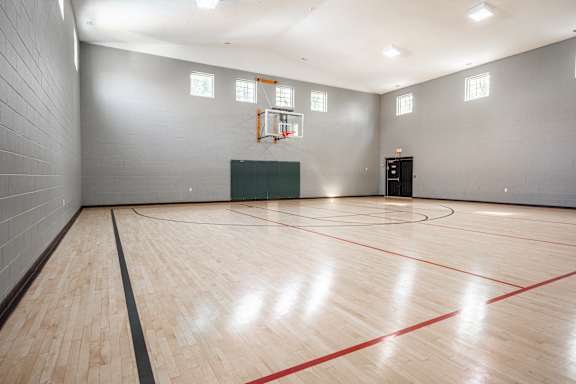 A basketball court with a green box and a basketball hoop at Latitudes Apartments, Indiana, 46237