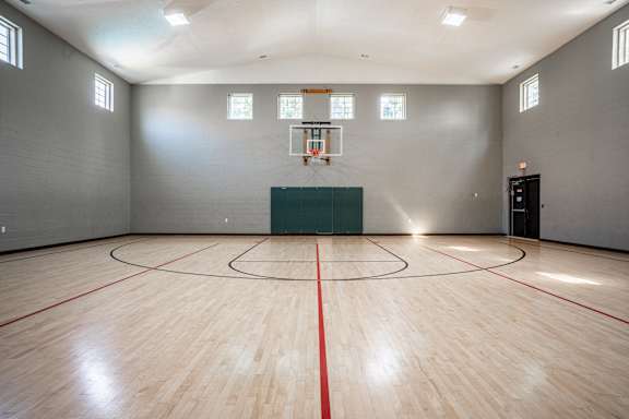 A basketball court with a green wall and a basketball hoop at Latitudes Apartments, Indiana, 46237
