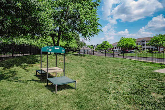 A green sign with a white arrow pointing to the right is on a pole in a grassy area at Latitudes Apartments, Indiana, 46237