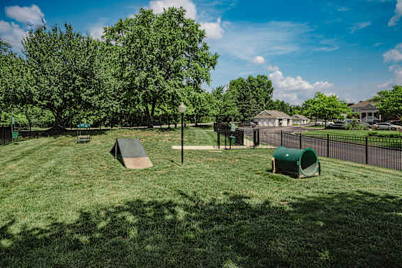 A playground with a slide and a green trash can at Latitudes Apartments, Indiana, 46237