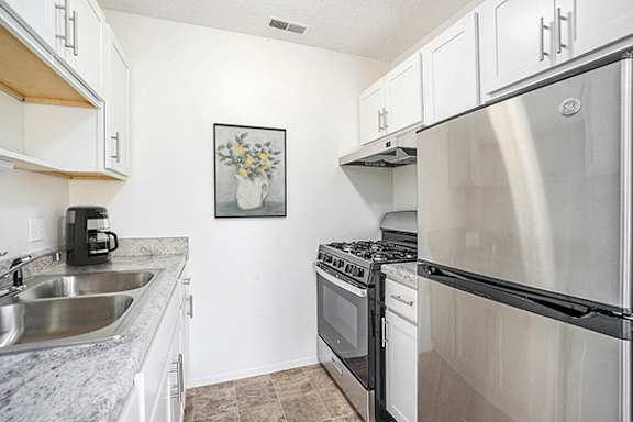 a kitchen with white cabinets and a gas stove Newport Village Apartments in Portage, MI 49002