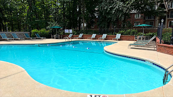 A large swimming pool surrounded by trees and chairs.