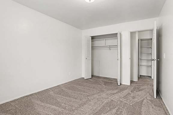 Vacant bedroom with dual closets and shelving at Fairlane Apartments, Springfield, Michigan