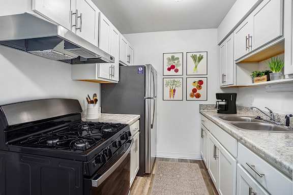 A kitchen with a stainless steel stove top and a refrigerator at Fairlane Apartments in Springfield, 49037